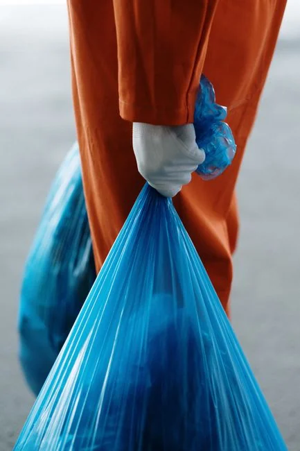 Un homme nettoie les vitres d'un gratte-ciel à l'aide d'un harnais, illustrant un travail en hauteur en milieu urbain.